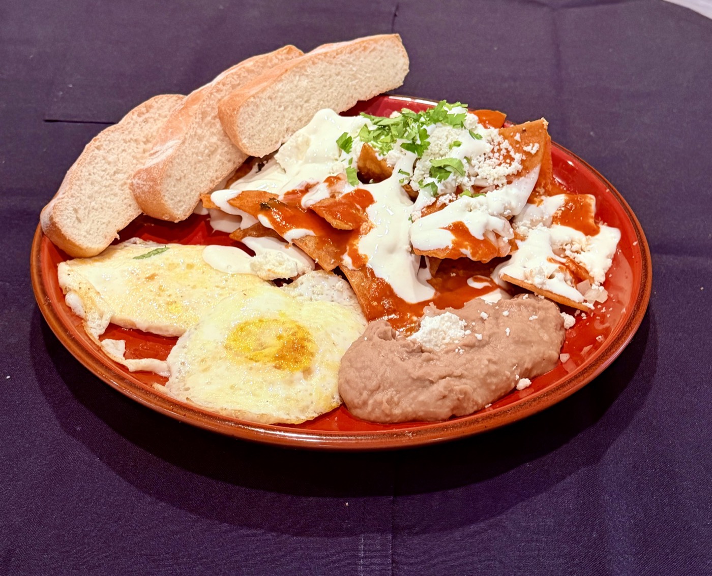 A chilaquiles plate at Pampano's with fried eggs, refried beans and bolillo bread