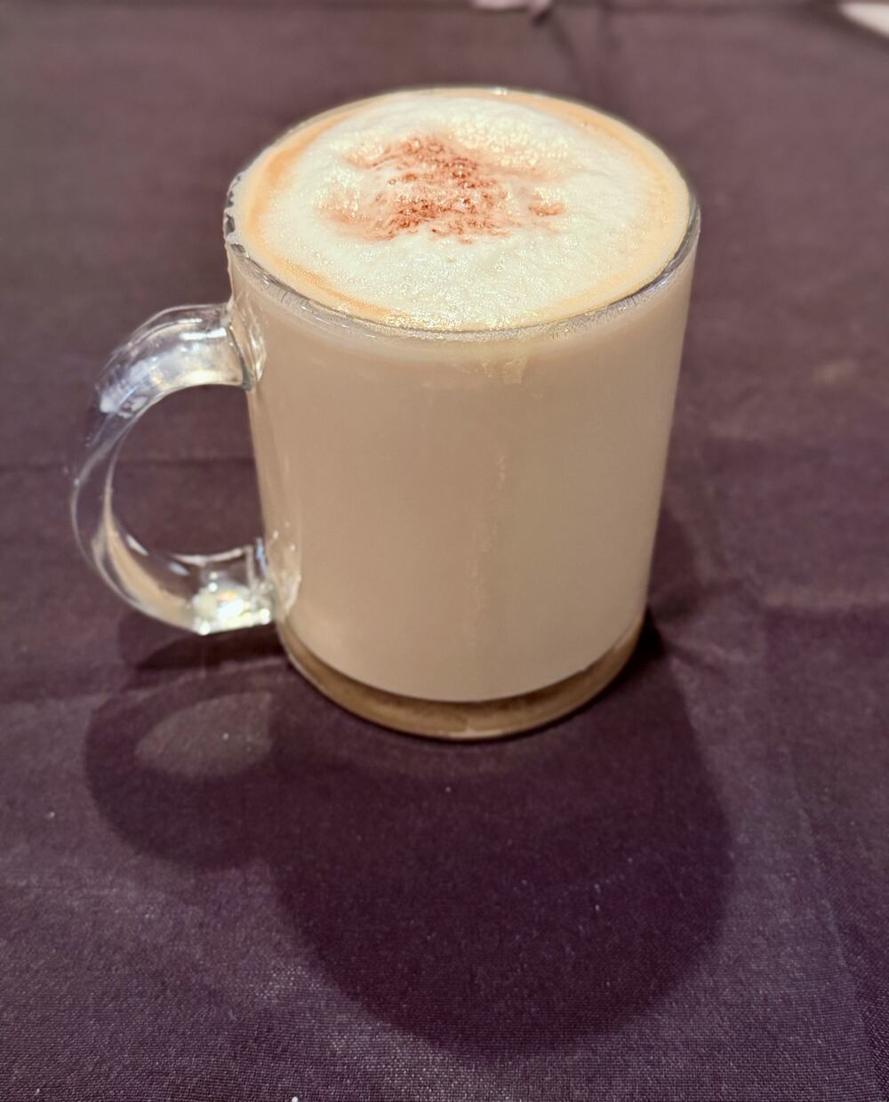 A cinnamon-dusted latte in a glass mug at Pampano's Cafe
